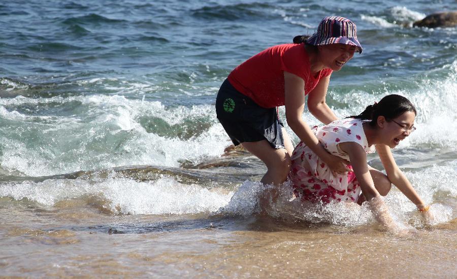 Tourists enjoy sunshine at seaside in Sanya