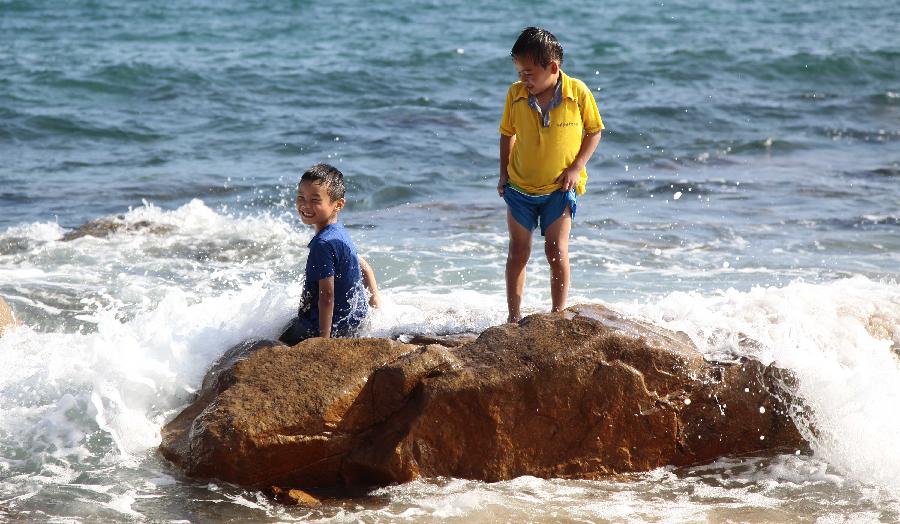 Tourists enjoy sunshine at seaside in Sanya