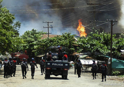 Policemen move towards burning villages in Sittway, capital of Rakhine state in western Myanmar, on June 12, 2012. Myanmar government is appealing for donation of relief supplies to victims left homeless by violent riot in the country's western Rakhine ethnic state. [Xinhua/Thet Htoo]