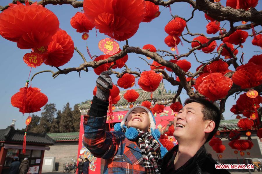 People look at red lanterns hung on a tree outside the south gate of Ditan Park in Beijing, capital of China, Feb. 8, 2013. The Spring Festival, the most important occasion for the family reunion for the Chinese people, falls on the first day of the first month of the traditional Chinese lunar calendar, or Feb. 10 this year. [Xinhua]