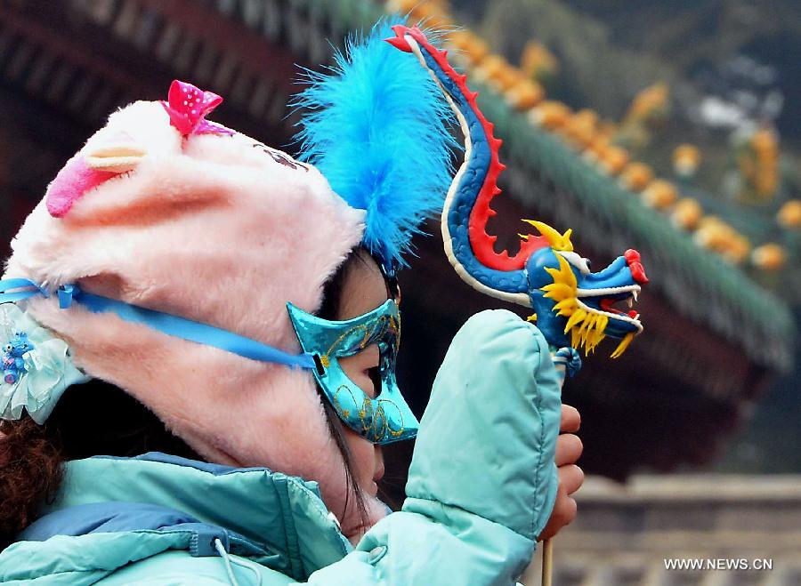 File photo taken on Jan. 23, 2012 shows a girl holding a dough figurine of dragon at a temple fair in Zhengzhou, capital of central China's Henan Province. 2012 was the Year of the Dragon in the Chinese Zodiac. Chinese Zodiac is represented by 12 animals to record the years and reflect people's attributes, including the rat, ox, tiger, rabbit, dragon, snake, horse, sheep, monkey, rooster, dog and pig. [Xinhua/Wang Song] 