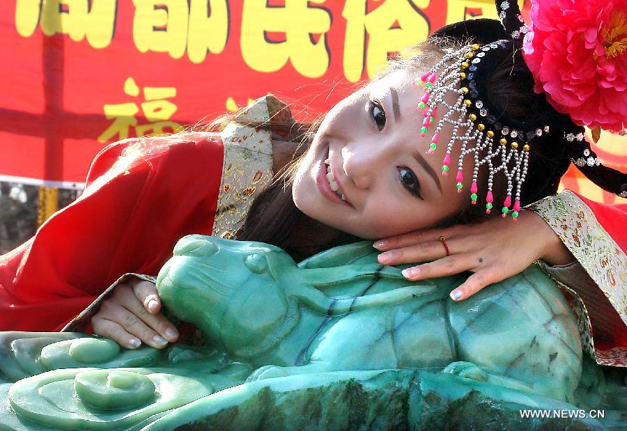 Photo taken on Jan. 31, 2011 shows a woman lying beside a jade handicraft of rabbit at a temple fair in Zhengzhou, capital of central China's Henan Province. 2011 is the Year of the Rabbit in the Chinese Zodiac. Chinese Zodiac is represented by 12 animals to record the years and reflect people's attributes, including the rat, ox, tiger, rabbit, dragon, snake, horse, sheep, monkey, rooster, dog and pig. [Xinhua/Wang Song]