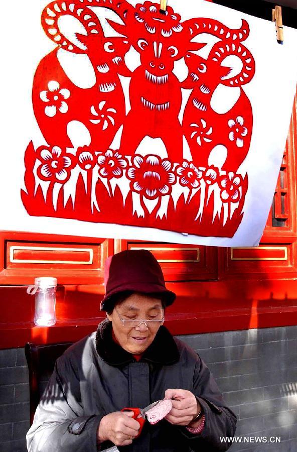 File photo taken on Feb. 6, 2003 shows a folk artist making a papercutting of sheep in a temple fair in Zhengzhou, capital of central China's Henan Province. 2003 was the Year of the Sheep in the Chinese Zodiac. Chinese Zodiac is represented by 12 animals to record the years and reflect people's attributes, including the rat, ox, tiger, rabbit, dragon, snake, horse, sheep, monkey, rooster, dog and pig. [Xinhua/Wang Song]