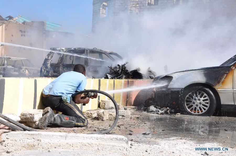 A firefighter tries to extinguish fire at the scene of car bomb blast that targeted a popular beachfront restaurant in Mogadishu, Somalia, Feb. 16, 2013.