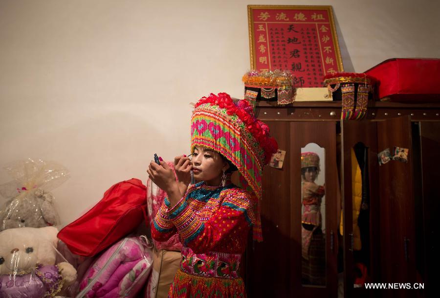 Zhang Lu, a bride of the Lisu ethnic group, dresses up herself before her wedding in Xinyu Village of Dechang County, southwest China's Sichuan Province, Feb. 15, 2013. 