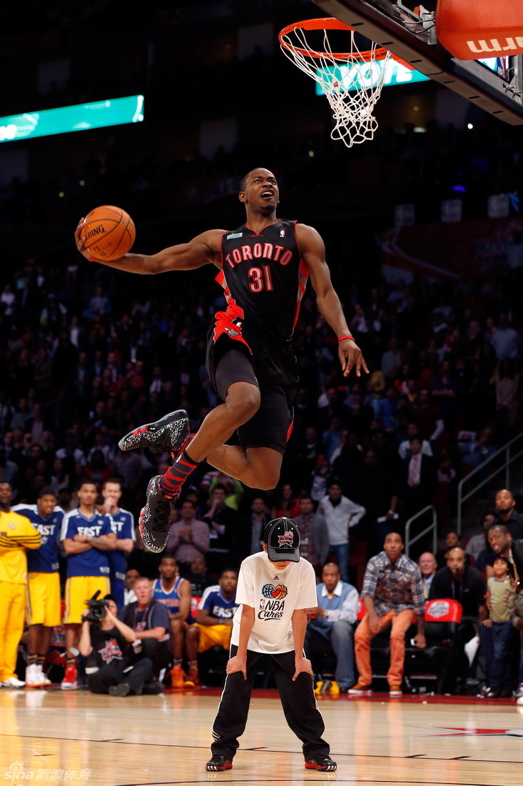 Toronto Raptors guard Terrence Ross leaps over a youngster as he attempts a dunk during the 2013 NBA all star slam dunk contest at the Toyota Center.