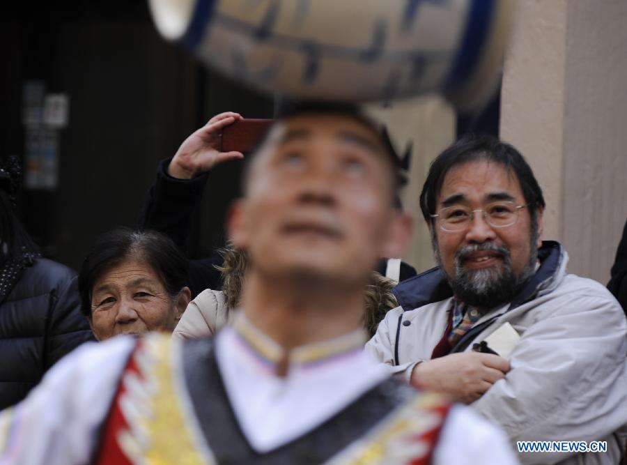 Spectators watch a performer spining a large ceramic pot on his forehead during a parade celebrating the Lunar New Year in the Chinatown in Yokohama, Japan, Feb. 17, 2013.