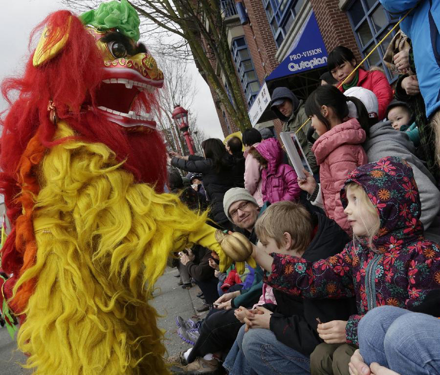 A lion dancer shakes hand with a girl during a Lunar New Year of the Snake celebration at Chinatown in Vancouver, Canada, Feb. 17, 2013. The grand parade is one of the largest in North America, drawing 70,000 people to the streets of Chinatown.