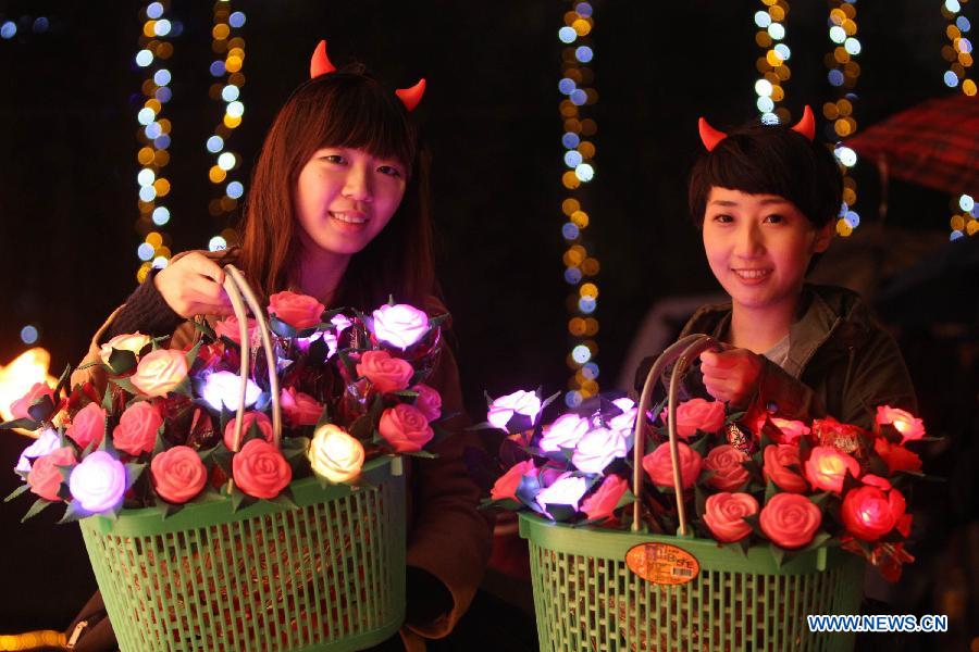 Two students sell rose shape lanterns in the shape of roses at a light show at Taipei Flora Expo Park in Taipei, southeast China's Taiwan, Feb. 21, 2013.