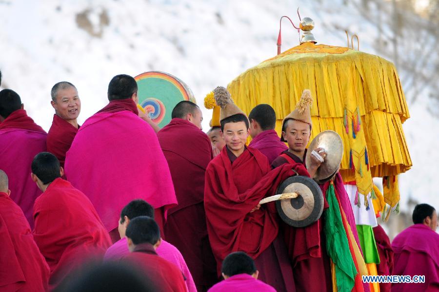 Lamas attend a Buddhist ritual displaying a gigantic Buddha tangka alongside a hillside for disciples' worship in Labrang Monastery in Xiahe, northwest China's Gansu Province, Feb. 22, 2013. 