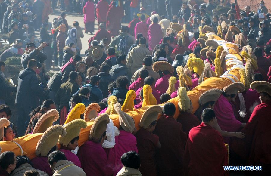 Lamas carry a gigantic Buddha tangka to a hillside for an anual display ritual in Labrang Monastery in Xiahe, northwest China's Gansu Province, Feb. 22, 2013. 