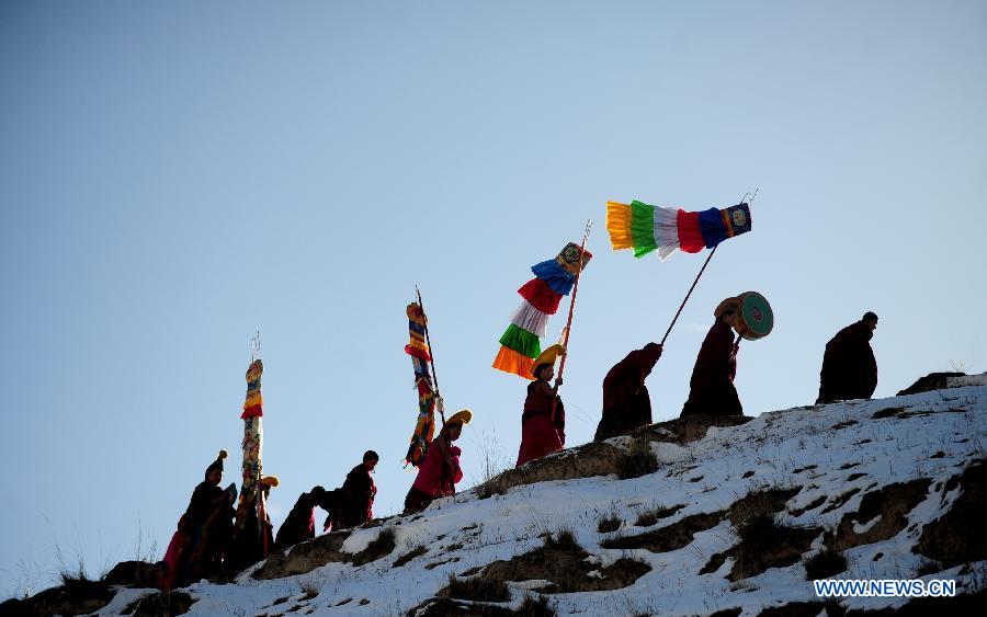 Lamas climb a hillside to attend a Buddhist ritual displaying a gigantic Buddha tangka alongside the hillside for disciples' worship in Labrang Monastery in Xiahe, northwest China's Gansu Province, Feb. 22, 2013.