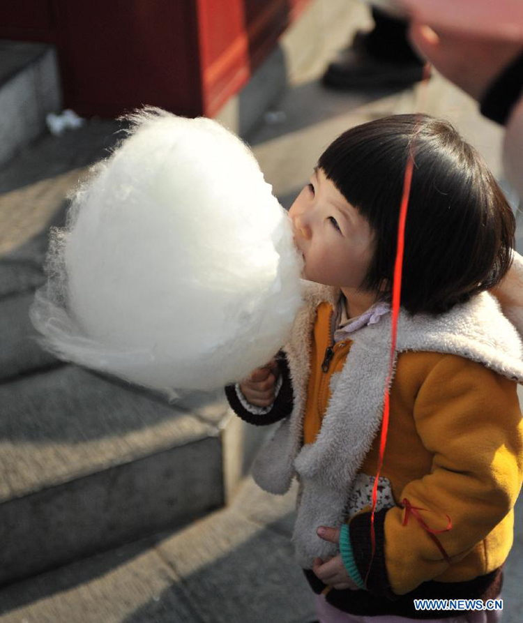 A child eats the cotton candy at an ancient street in north China&apos;s Tianjin Municipality, Feb. 23, 2013. As the Lantern Festival falls on the next day, various lanterns were set up at the ancient street, which offers a place for local citizens in Tianjin to experience the culture of the festival.