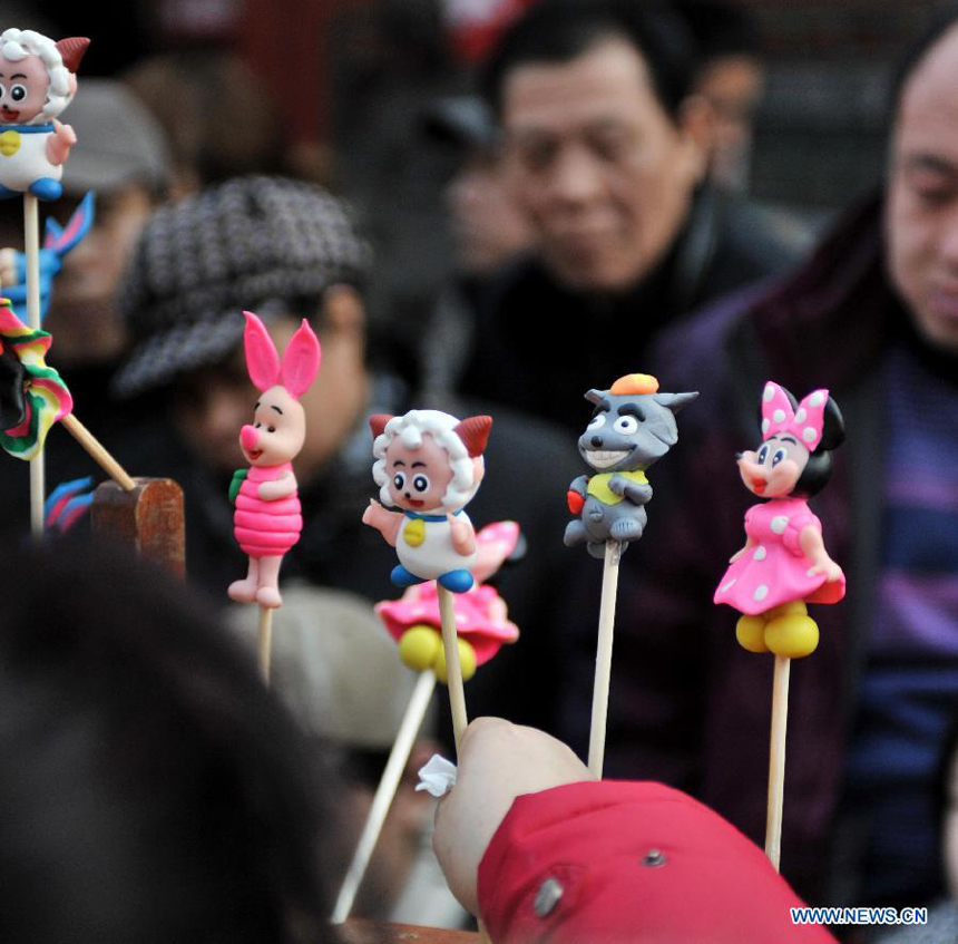 Visitors are attracted by toys made of dough at an ancient street in north China&apos;s Tianjin Municipality, Feb. 23, 2013. As the Lantern Festival falls on the next day, various lanterns were set up at the ancient street, which offers a place for local citizens in Tianjin to experience the culture of the festival. 