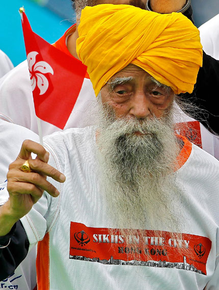 Fauja Singh, 101, raises a Hong Kong flag after finishing a 10-kilometer race in the city's annual marathon yesterday.