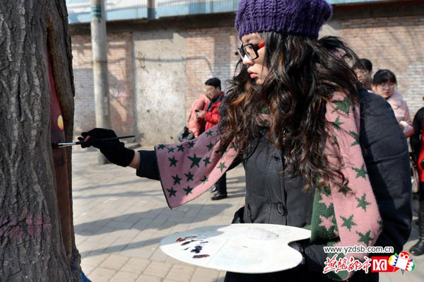 Student painter Wang Yue shows her talent by painting tree holes in Shijiazhuang, capital city of Hebei Province. [Photo/yzdsb.com.cn]