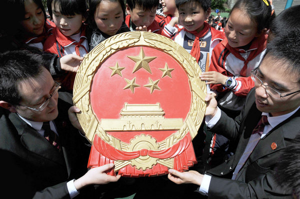 Judges tell primary school students in Dayang township, Chongqing, about the national emblem to help them establish awareness of the rule of law. [Photo/China Daily] 
