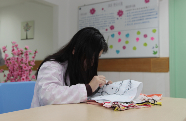 A patient uses embroidery as part of the treatment for her illness at the hospital, which has treated more than 6,000 depressed patients during the past four years. [Photo/China Daily]