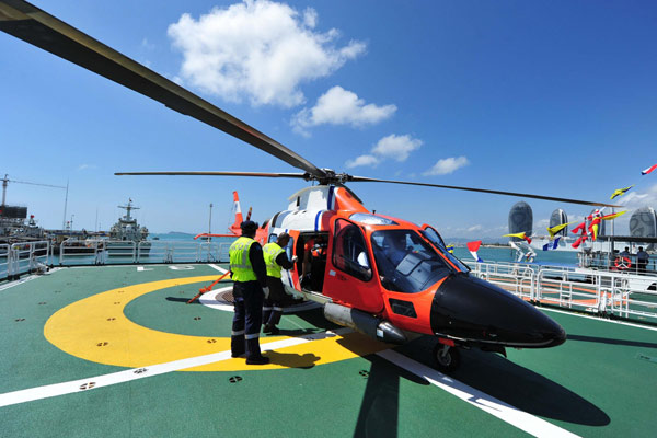 Staff members examine the helicopter carried by marine patrol ship Haixun 31 before it sails out of the port of Sanya, South China's Hainan province, Feb 28, 2013. [Photo/Xinhua]