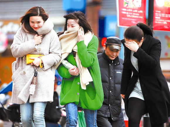 People walk in the strong wind in Jiangcheng, Hubei Province, on March 1. A strong cold front is moving from north to south over the next couple of days, bringing temperature drops and strong winds to south China, the National Meteorological Center. [Photo from ctjb.cnhubei.com]