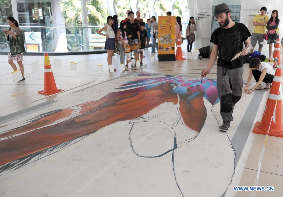 An artist draws on the ground in Bangkok, Thailand, March 2, 2013. 