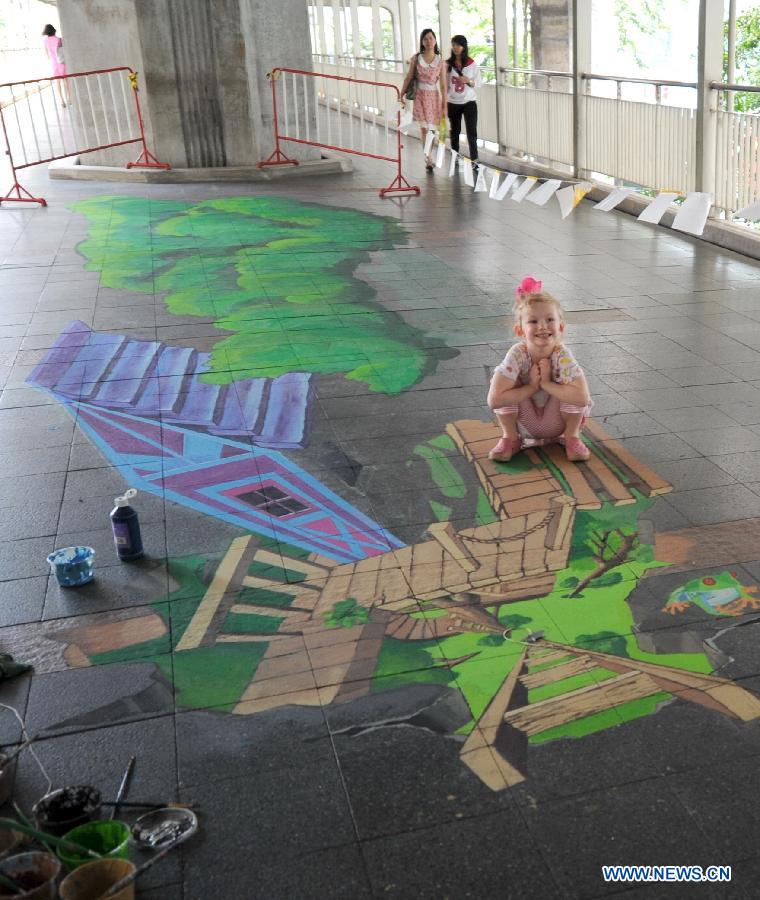 A girl poses for photos beside a street painting in Bangkok, Thailand, March 2, 2013.