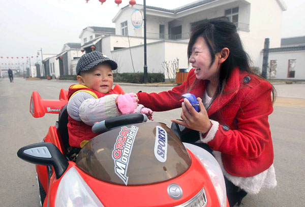 A woman and her son have fun at a newly constructed community in Zhangzhuang village, Pingdingshan, Henan province, in March 2012. [Photo/Xinhua]