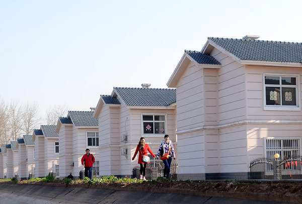 Villagers pass newly built houses at Yuantun village in Jiaozuo city, Henan province. The province’s urban population accounted for 42.2 percent of its total population at the end of 2012, a year-on-year rise of 1.8 percentage points. [Photo/Xinhua] 