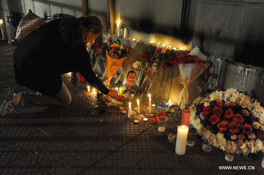 A woman lights candles in front of a memorial place at the Venezuelan Embassy to Chile after the news of Venezuelan President Hugo Chavez's death was released, in Santiago, capital of Chile, on March 5, 2013. Venezuelan President Hugo Chavez died on March 5.