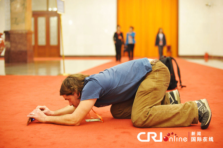 A foreign journalist reports China's political meetings near the Great Hall of the People in Beijing on March 7, 2013. 