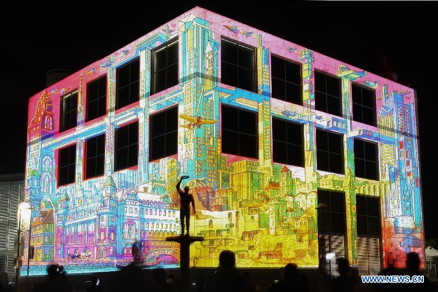 A statue is silhouetted against a large scale projection illuminating the The National Science and Technology Centre in Canberra, March 9, 2013.