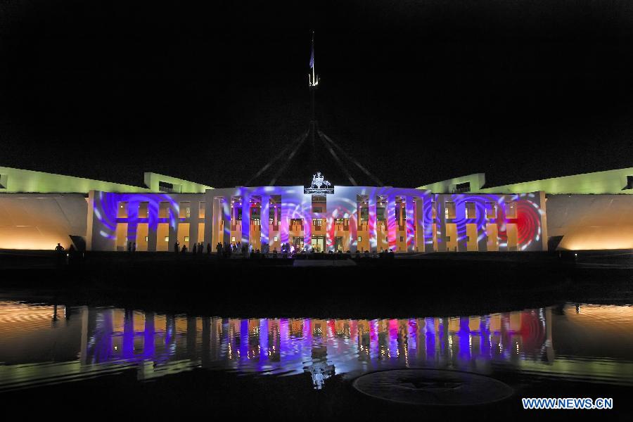 Onlookers watch the light show on a wall of the Museum of Australian Democracy at the Old Parliament House as it is illuminated by a large scale projection, in Canberra, March 9, 2013. 