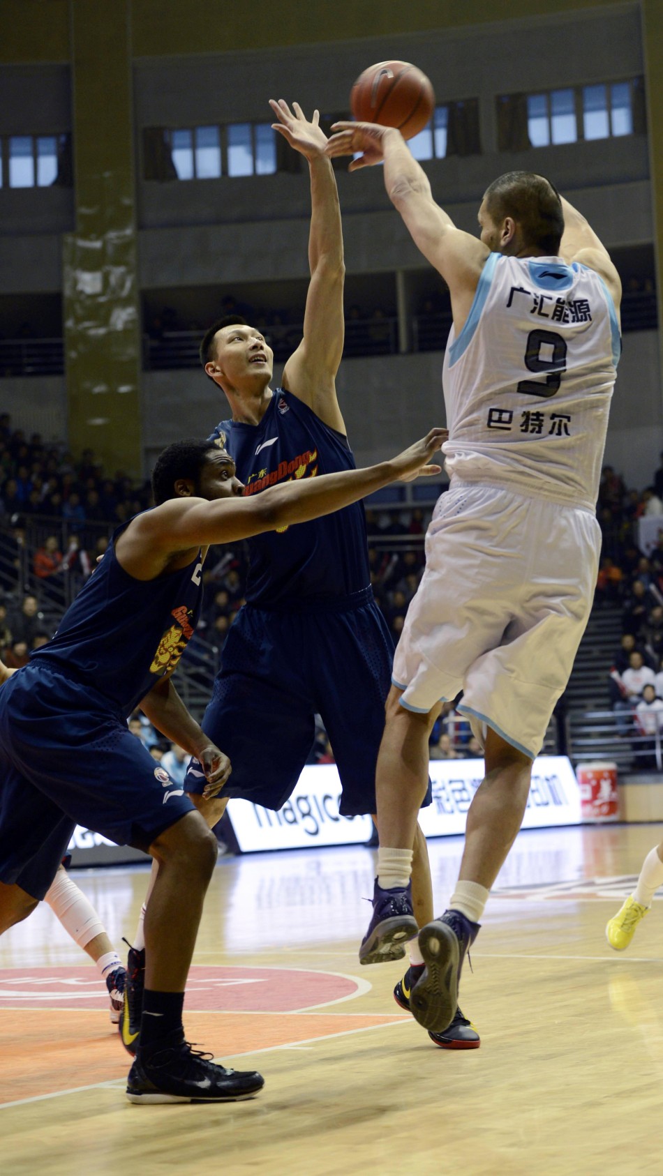 Batter of Xinjiang passes the ball in the face of Yi Jianlian in Game 1 of CBA semifinals between Guangdong and Xinjiang on March 10, 2013.