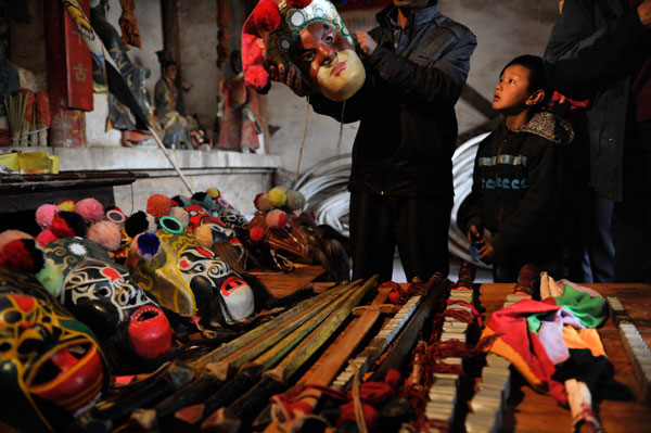 Villagers prepare masks for the Guansuo play in Xiaotun village, Chengjiang county in Yunnan province. The play is a ceremony to pray for good weather and a bumper grain harvest. [Photo/China News Service]