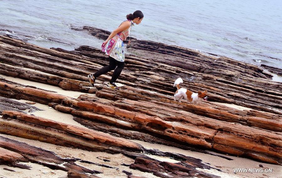 A tourist goes for a walk with her pet dog on the Tung Ping Chau island of south China's Hong Kong, March 17, 2013. 