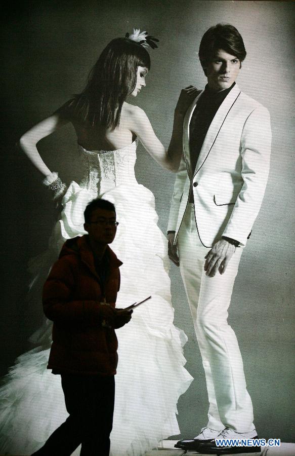 A man walks past a poster of wedding photo during the 2013 Xici Wedding Expo for Spring in Nanjing, capital of east China's Jiangsu Province, March 16, 2013.