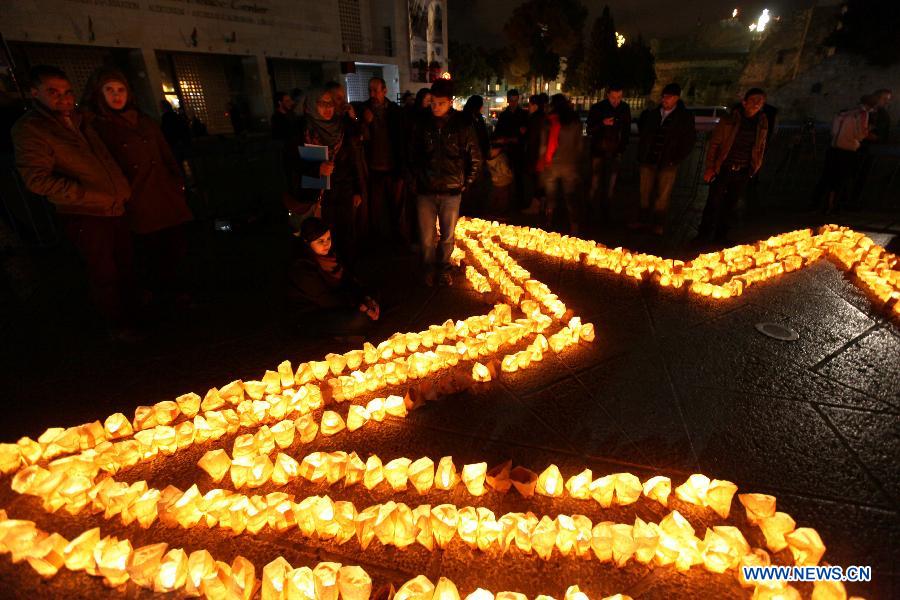 Palestinians gather around candles to mark the &apos;Earth Hour&apos; near the Church of Nativity in the West Bank city of Bethlehem on March 23, 2013. (Xinhua/Luay Sababa)