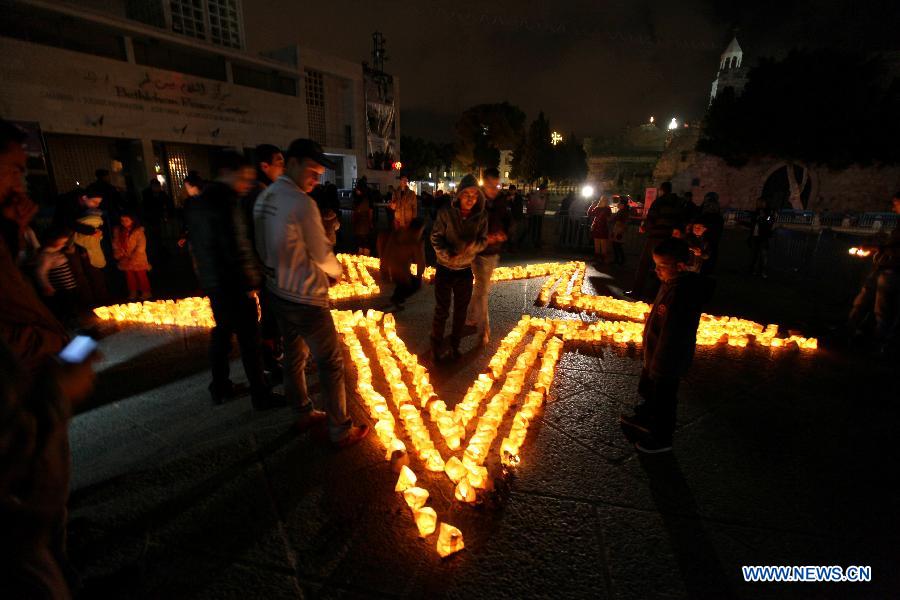 Palestinians gather around candles to mark the &apos;Earth Hour&apos; near the Church of Nativity in the West Bank city of Bethlehem on March 23, 2013. (Xinhua/Luay Sababa)