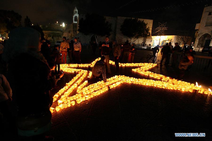 Palestinians gather around candles to mark the &apos;Earth Hour&apos; near the Church of Nativity in the West Bank city of Bethlehem on March 23, 2013. (Xinhua/Luay Sababa)