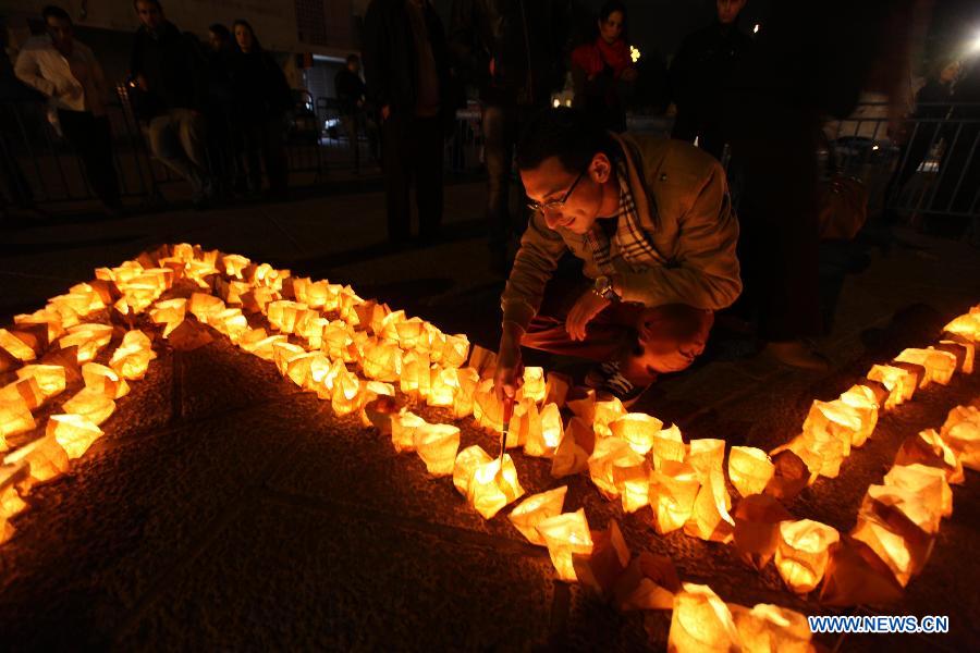 Palestinians gather around candles to mark the &apos;Earth Hour&apos; near the Church of Nativity in the West Bank city of Bethlehem on March 23, 2013. (Xinhua/Luay Sababa)