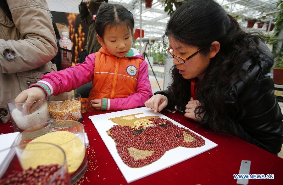 A visitor helps her child make a decorative painting with grains and beans during the 1st Agriculture Carnival at the Strawberry Expo Park in Changping District, Beijing, capital of China, March 23, 2013. Opened Saturday, the carnival will continue till May 12, highlighting the latest agricultural science, technologies and creative agricultural projects. (Xinhua/Li Xin)