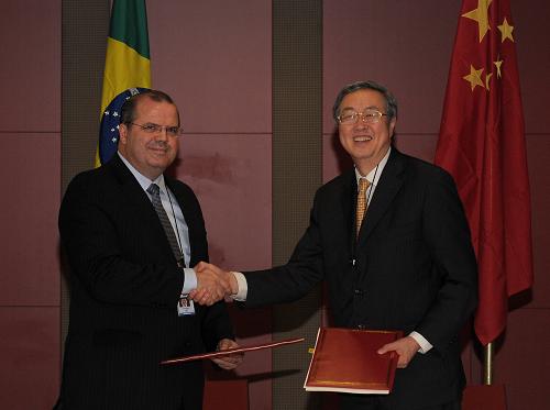 The Governor of the People's Bank of China Zhou Xiaochuan shakes hands with his Brazilian counterpart after signing the currency swap agreement in Durban, South Africa on March 26, 2013. [Xinhua photo]