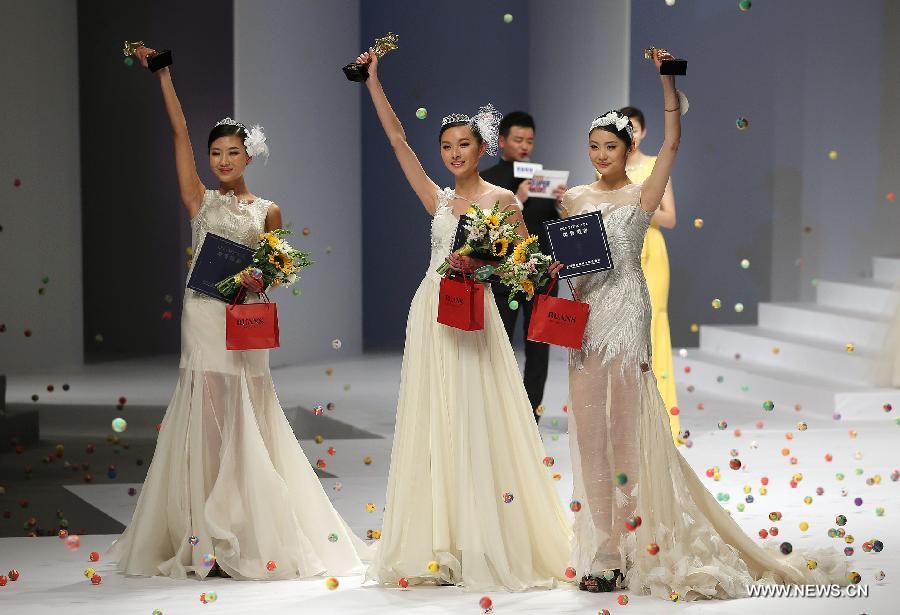 Champion Zhang Lingyue (C), runner-up Zhao Siyu (L) and second runner-up Lei Shuhan greet the audience during the 8th China Super Model Final Contest in Beijing, capital of China, March 30, 2013. [Wan Xiang/Xinhua]