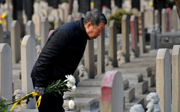 A man bows to a tombstone in a cemetery garden in Beijing, March 30, 3013. [Photo/icpress]  