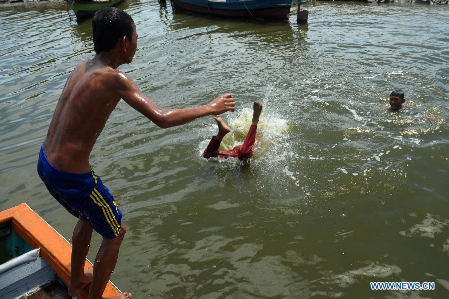 An Indonesian boy jumps into water as he and others play in a river at a slum in Bekasi, West Java Province, Indonesia, on April 8, 2013. 