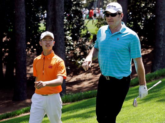 Guan Tianlang walks with Nick Faldo during the Par-3 competition before the Masters golf tournament Wednesday.