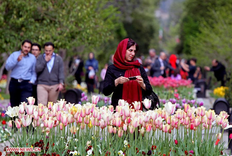 People enjoy themselves beside flowers at Mellat park in northern Tehran, Iran, on April 14, 2013. Spring flowers blossom here as the temperature keeps rising recently. (Xinhua/Ahmad Halabisaz) 