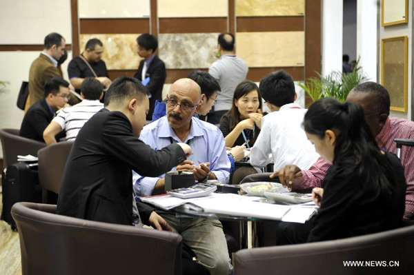 Exhibitors and businessmen talk during the 113th China Import and Export Fair in Guangzhou, capital of south China's Guangdong Province, April 15, 2013. The three-week 113th China Import and Export Fair kicked off here on Monday. [Liang Xu/Xinhua]