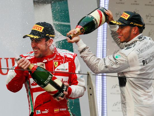 Ferrari driver Fernando Alonso is sprayed with champagne by second placed Mercedes driver Lewis Hamilton of Britain after winning the Chinese Formula One Grand Prix in Shanghai, China.