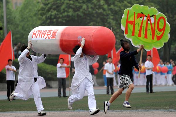 Two college students carrying a model of a capsule chase another student holding a banner reading 'H7N9' during a performance at the opening ceremony of the sports meeting hosted by Chongqing University in Southwest China's Chongqing municipality on Friday. The characters on the capsule model read 'H7N9 killer'.[Photo/China News Service]